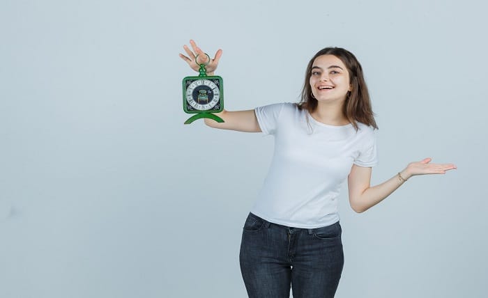 young girl pretending show something while holding clock t shirt jeans looking happy front view 176474 58875