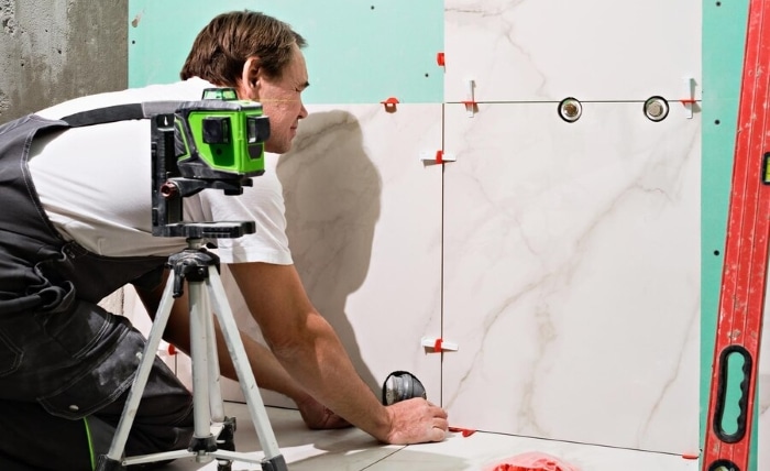 professional master man laying ceramic tiles wall bathroom portrait experienced repairman laying large size porcelain tilesconstruction worker checking tile installation with laser level 166373 2067