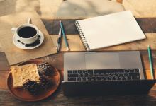 A cozy home office setup with a laptop, coffee, notebook, and toast on a wooden table, representing productive remote work routines